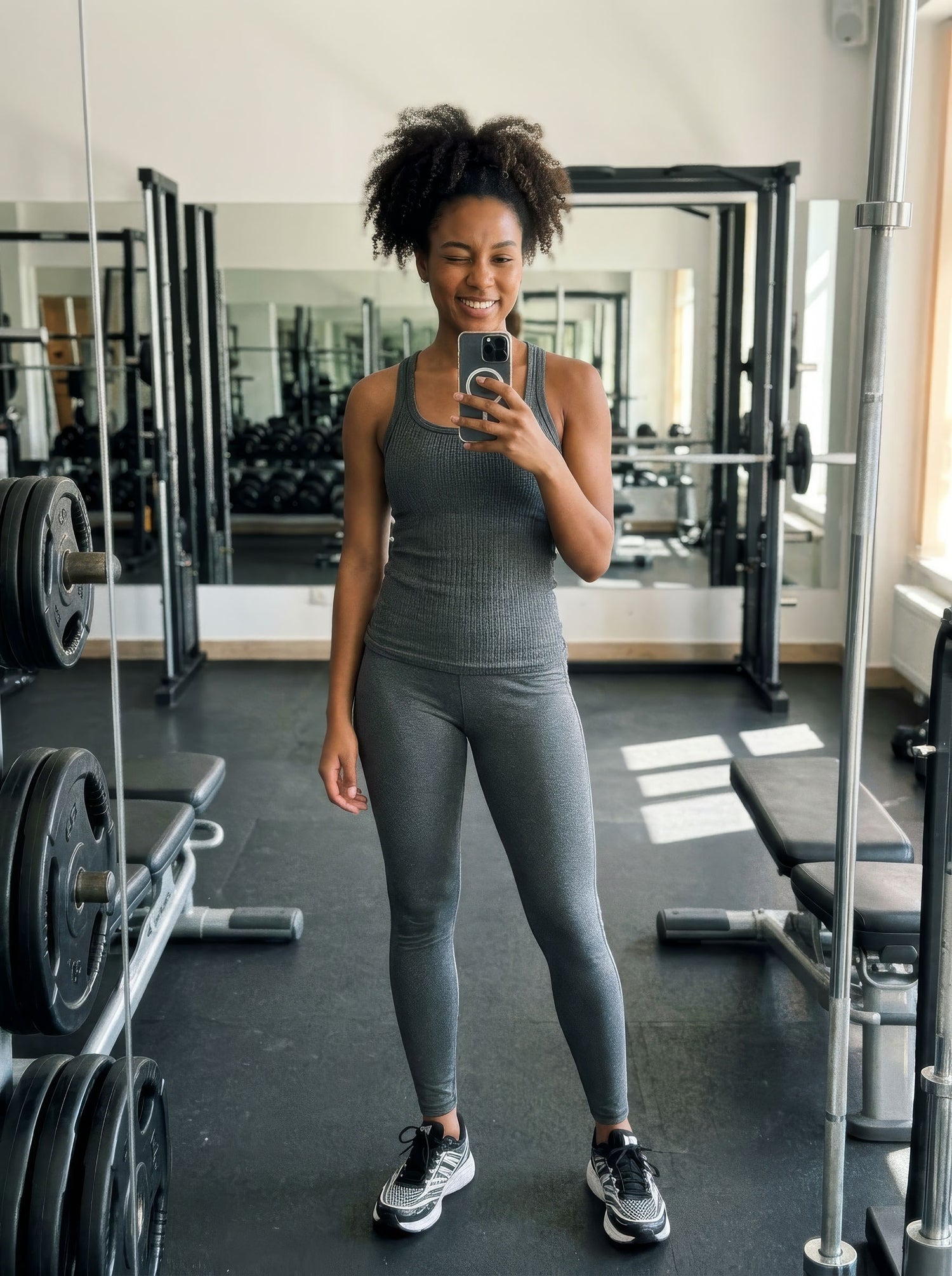 Woman taking a mirror selfie in a gym wearing the Meadow Athlete's outfit.